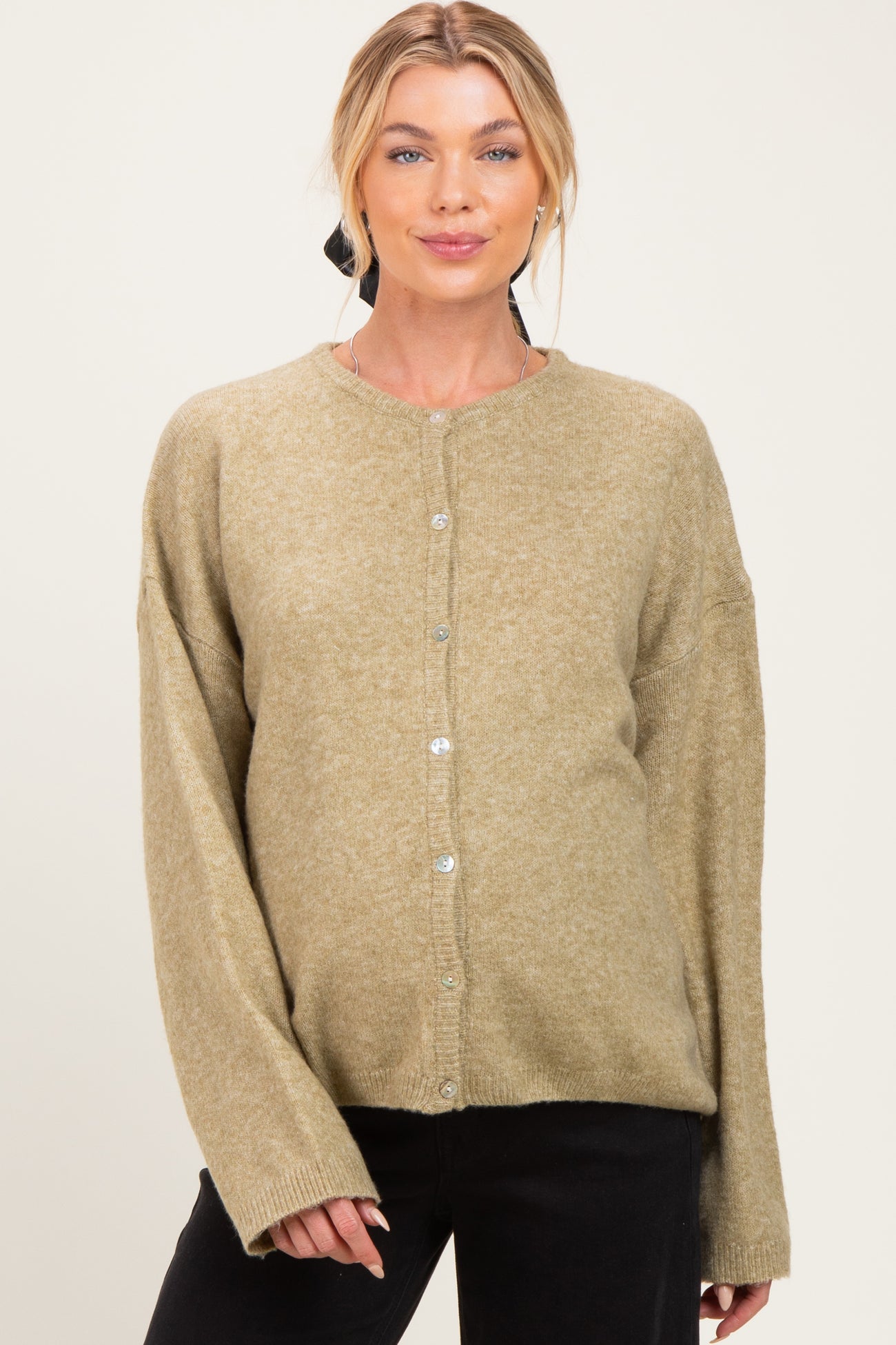 woman wearing a light olive green maternity cardigan with buttons and relaxed fit, showing her baby bump