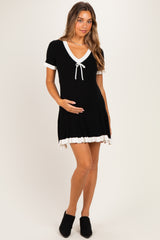 woman wearing a black maternity dress with white trim and a bow, holding her baby bump