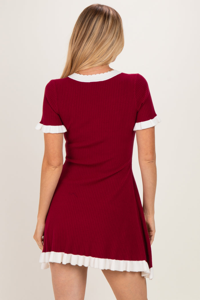 woman wearing a red ribbed dress with white ruffle details on the sleeves and hem, shown from the back