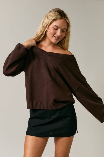 woman wearing a brown off-the-shoulder sweater and a black mini skirt