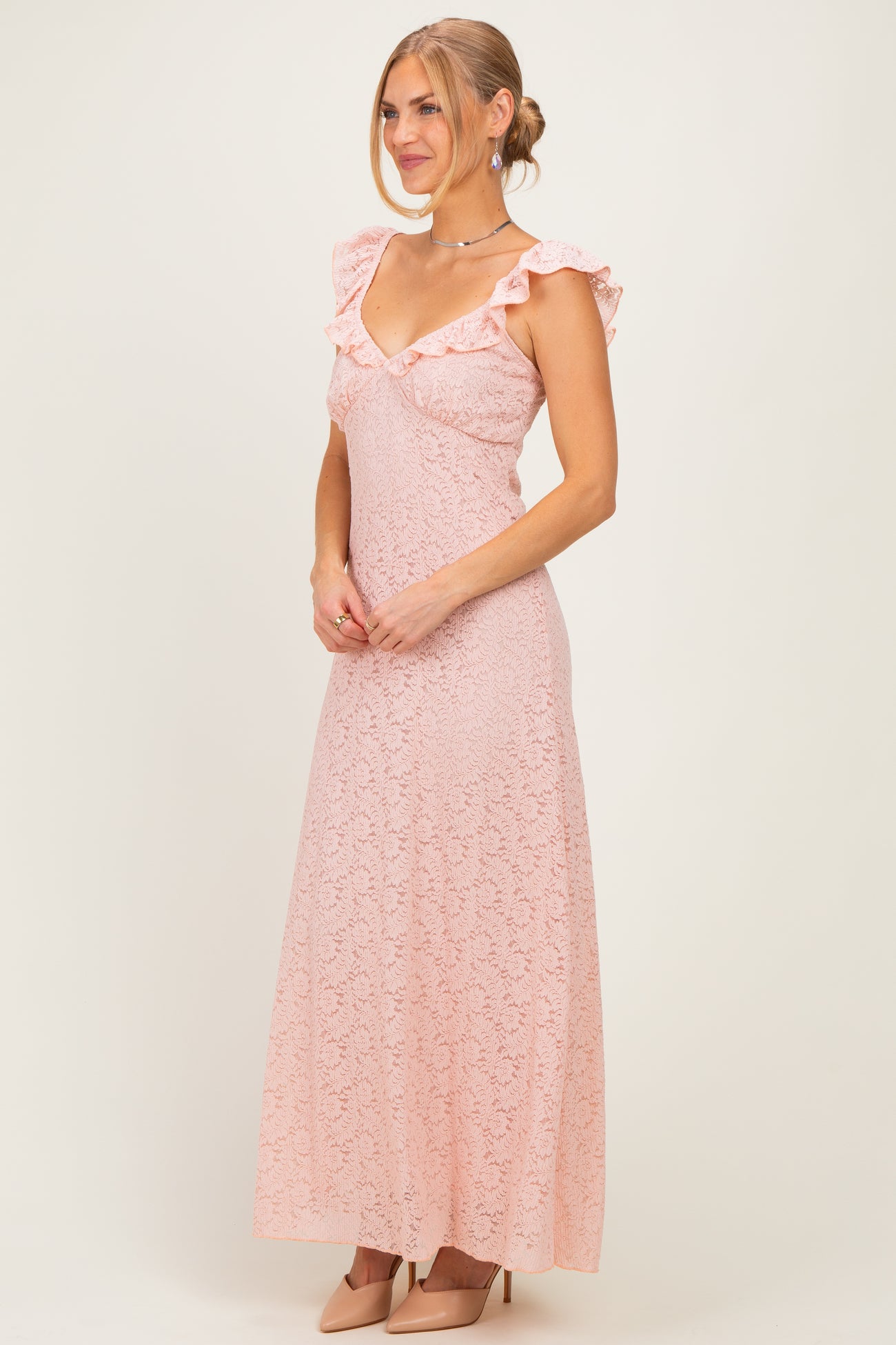 woman wearing a blush pink lace maxi dress with ruffle sleeves and a deep V-neckline