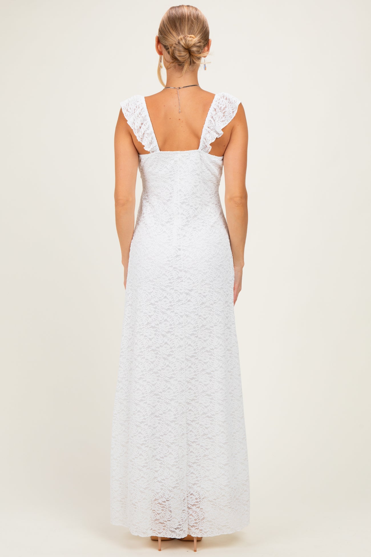 woman wearing a white lace long dress with ruffled straps, shown from the back
