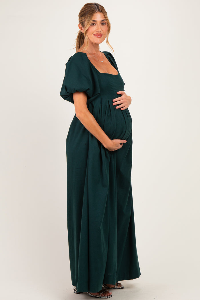woman wearing a dark green short sleeve maternity dress holding her baby bump