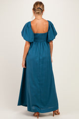 woman wearing a teal maternity maxi dress with puff sleeves and a smocked bodice, showing her back
