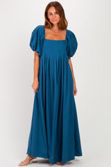 woman wearing a teal puff sleeve maxi dress with a square neckline and pleated details