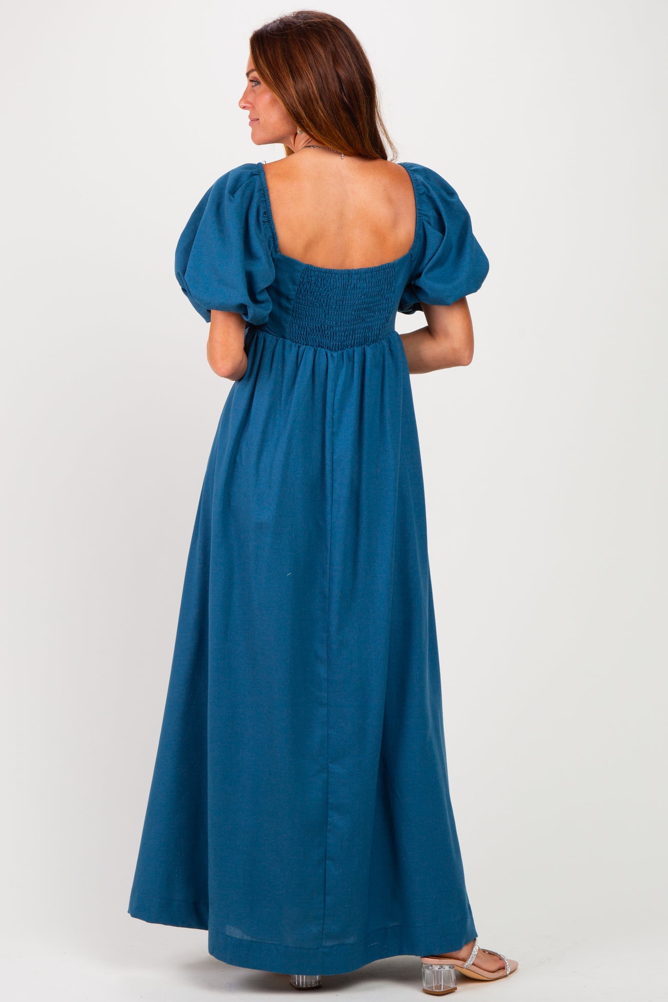 woman wearing a teal puff sleeve maxi dress with a smocked back and a square neckline, viewed from the back