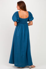 woman wearing a teal puff sleeve maxi dress with a smocked back and a square neckline, viewed from the back