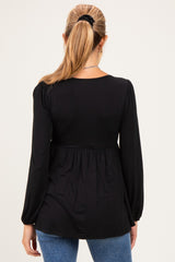 woman wearing a black long sleeve maternity top with a gathered waist and back view, styled with blue jeans
