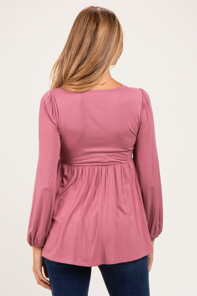 woman wearing a dusty rose long sleeve maternity top with a pleated waist and relaxed fit, showing her back