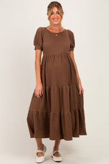 woman wearing a brown tiered maternity dress with short puff sleeves and a visible baby bump