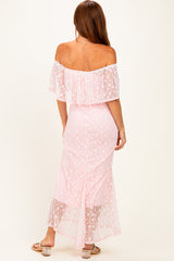 woman wearing a light pink off-the-shoulder maxi dress with a ruffled overlay and sheer lace details