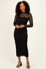 woman wearing a black lace long sleeve midi dress with a fitted silhouette and strappy black heels