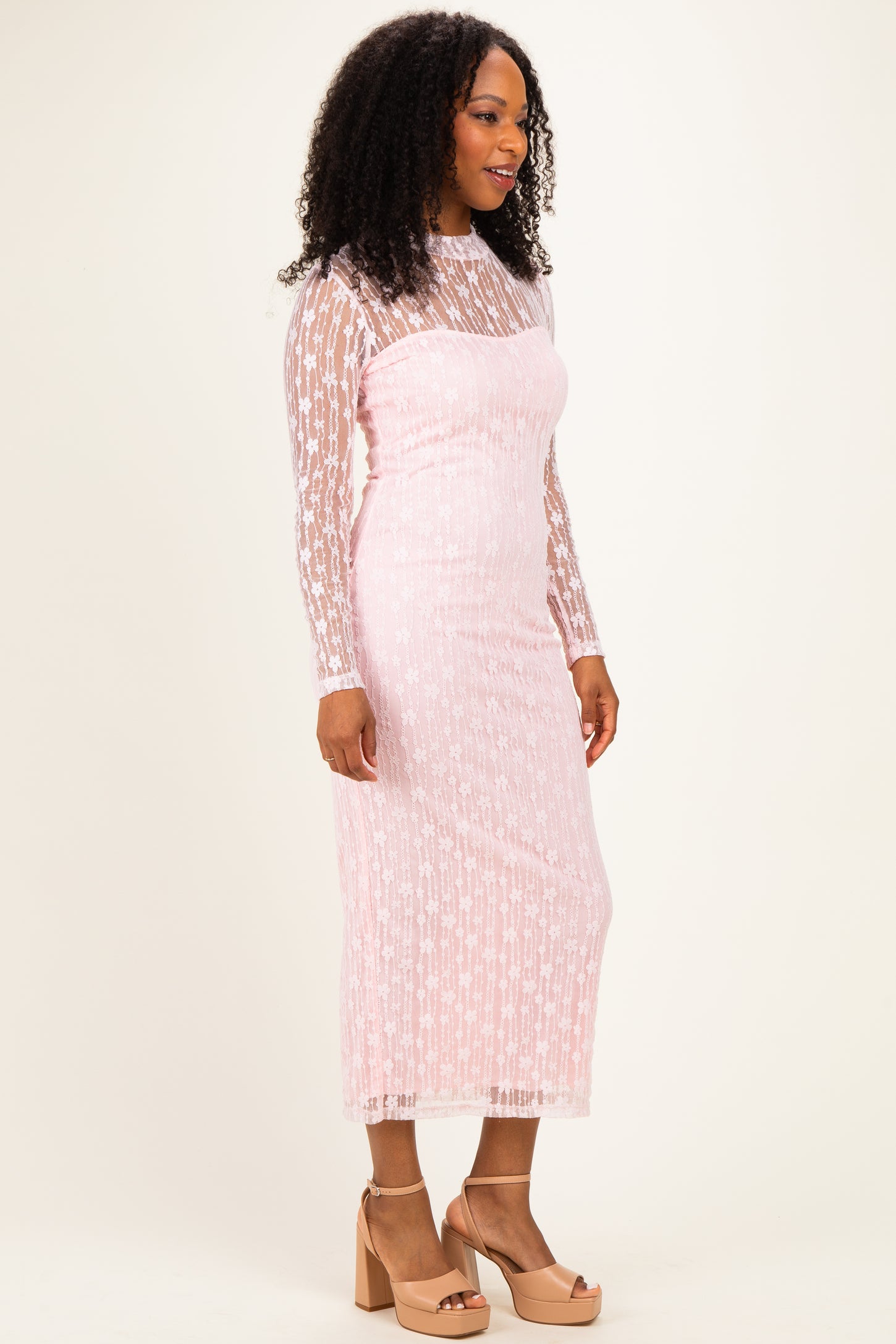 woman wearing a pink long sleeve lace dress with star patterns and a fitted style, paired with beige block-heeled sandals