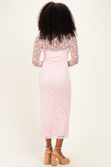 woman wearing a pink lace midi dress with long sleeves, showing the back view and styled with tan block heels