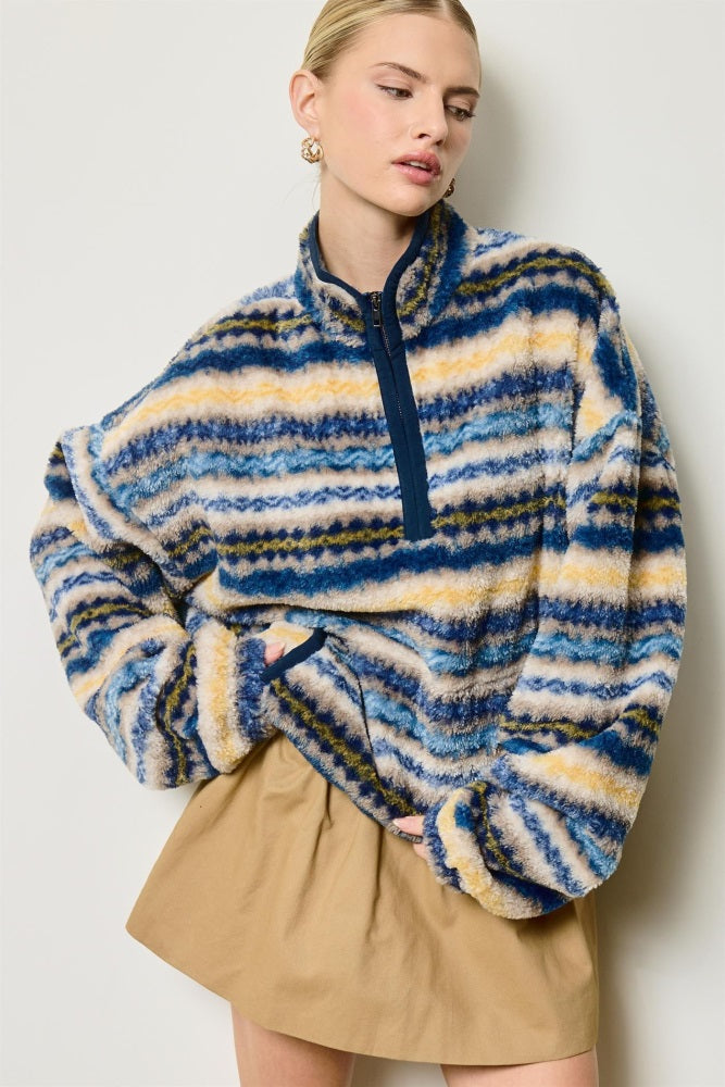 woman wearing a blue and tan striped fleece pullover with a half zip and relaxed fit, paired with a beige skirt
