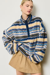 woman wearing a blue and tan striped fleece pullover with a half zip and relaxed fit, paired with a beige skirt
