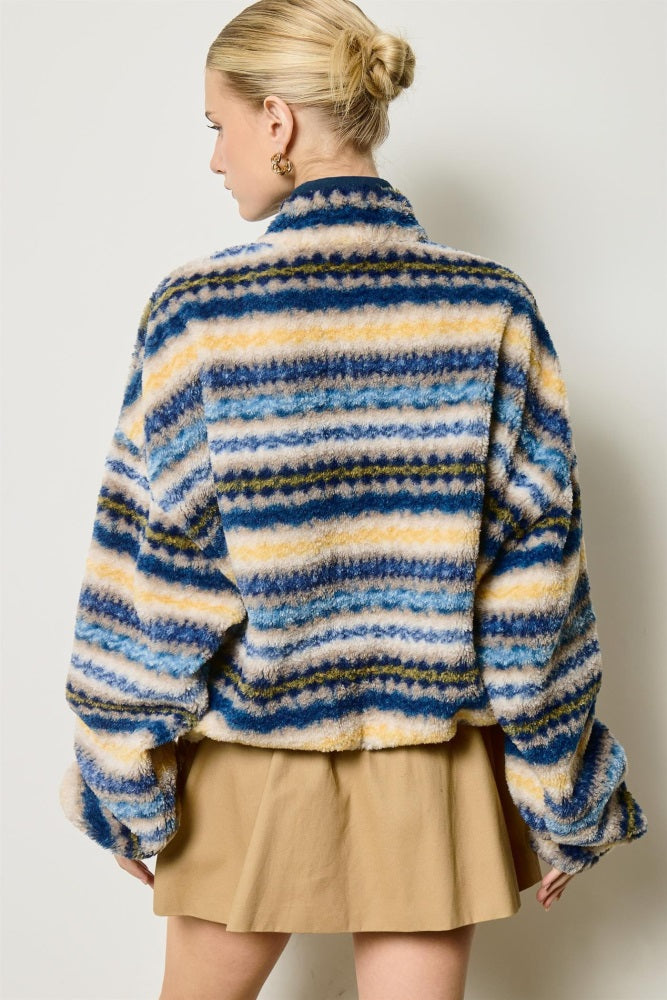 woman wearing a multicolored striped fluffy jacket with a relaxed fit, styled with a tan skirt