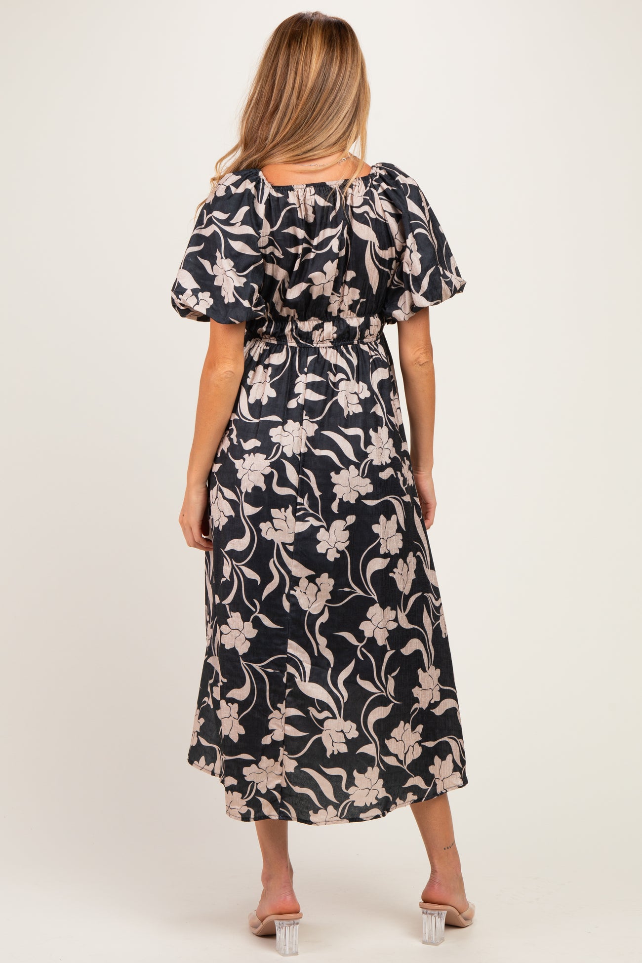 woman wearing a floral patterned black maternity dress with puff sleeves and an elastic waist, seen from the back