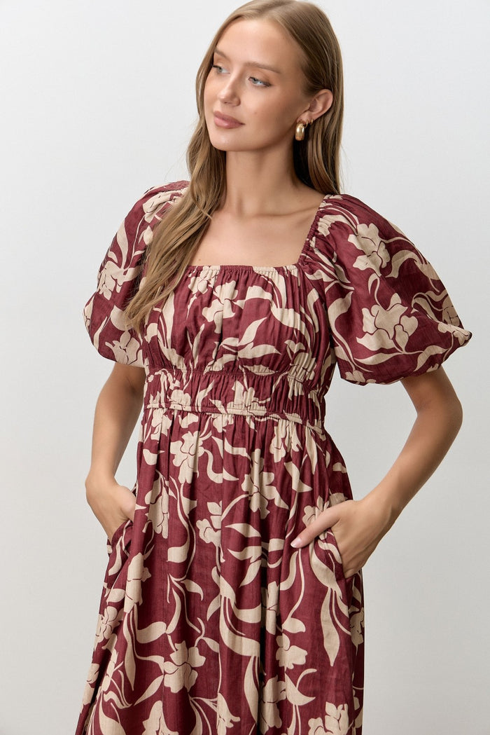 woman wearing a burgundy floral print midi dress with puff sleeves and pockets