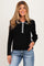 woman wearing a black ribbed maternity top with a white buttoned collar and long sleeves