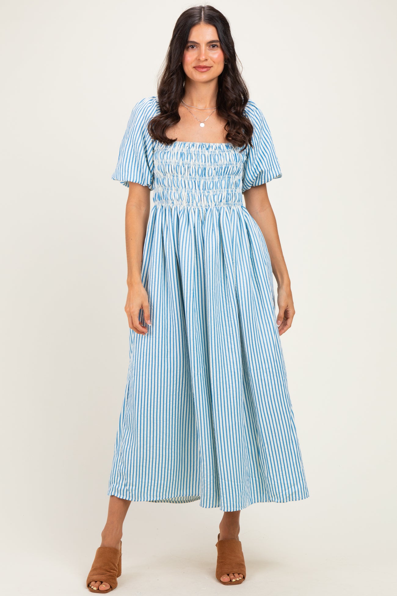 woman wearing a blue and white striped puff sleeve midi dress with smocking detail and tiered skirt