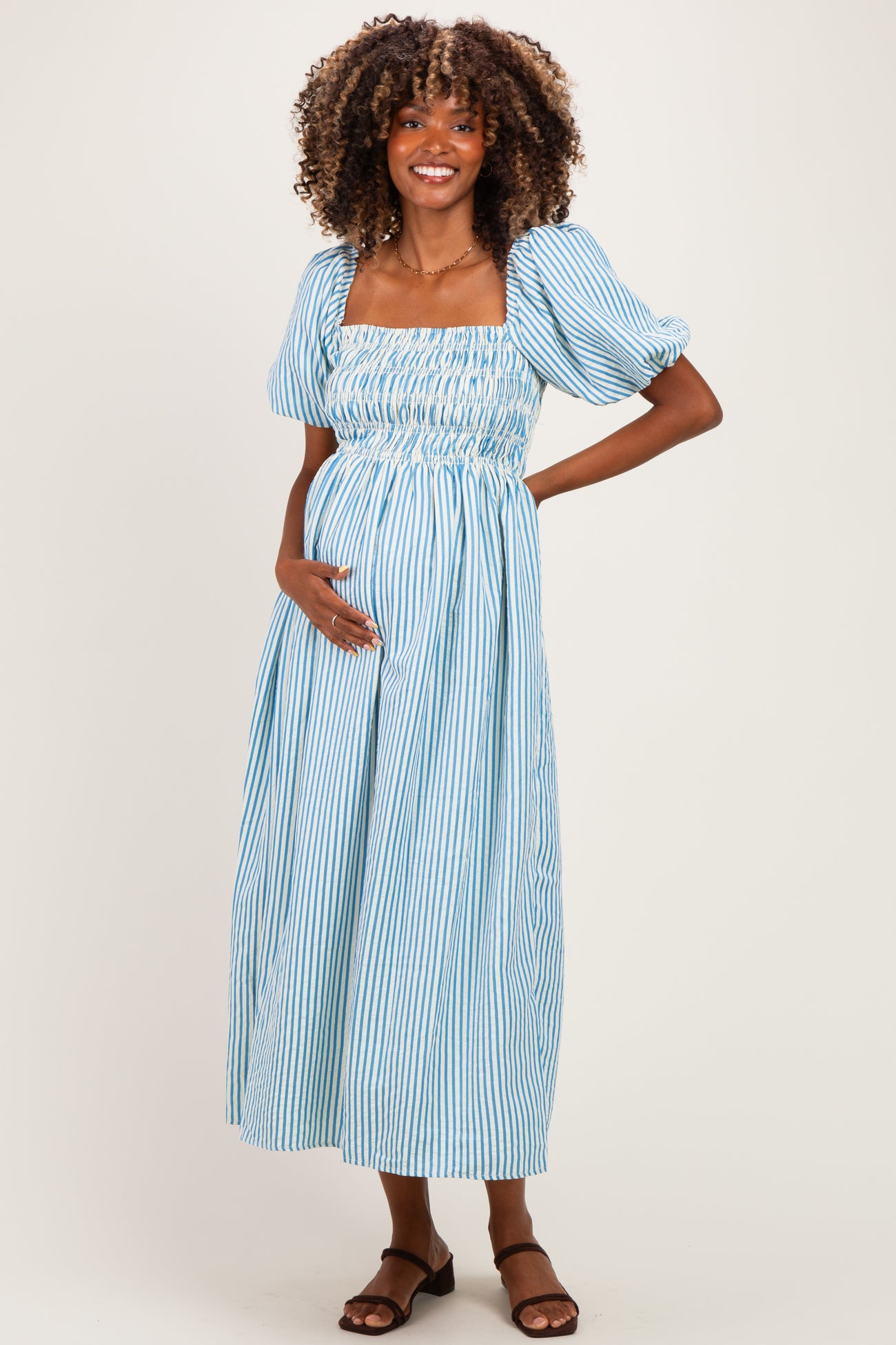 woman wearing a light blue and white striped maternity dress with puff sleeves and a baby bump visible