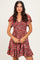 woman wearing a red floral short sleeve dress with a smocked bodice and tiered skirt