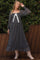 woman wearing a black and white patterned maternity dress with long sleeves and a bow detail, posing outdoors