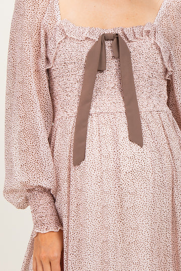 maternity wear in a blush pink dress with a smocked bodice and a bow at the neckline, featuring long puff sleeves