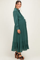 woman wearing a dark green long sleeve maternity dress with a tiered skirt and visible baby bump