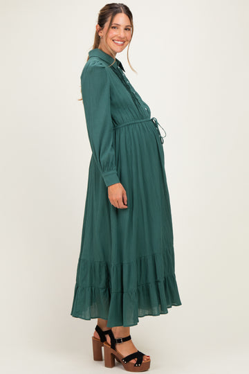 woman wearing a dark green long sleeve maternity dress with a tiered skirt and visible baby bump