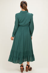 woman wearing a dark green maternity dress with a tiered skirt and long sleeves, showing the back view