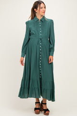 woman wearing a green maternity dress with a button-up front and ruffled hem, styled with a tie waist and long sleeves