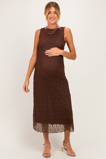 woman wearing a brown lace maternity dress and gently holding her baby bump