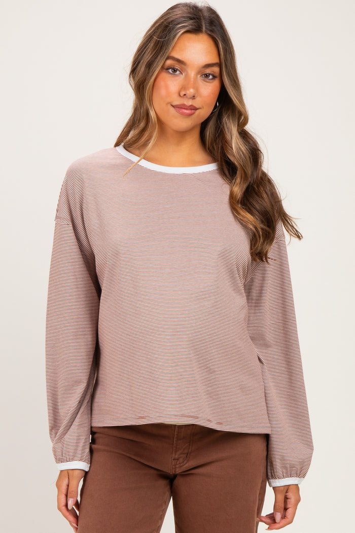 woman wearing a light brown striped maternity top with long sleeves and a white neckline, showing a baby bump