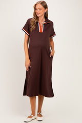 woman wearing a brown maternity polo dress with a striped collar and side slits, showcasing her baby bump