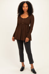 woman wearing a brown long sleeve button-up peplum top with a relaxed fit and paired with black cropped jeans