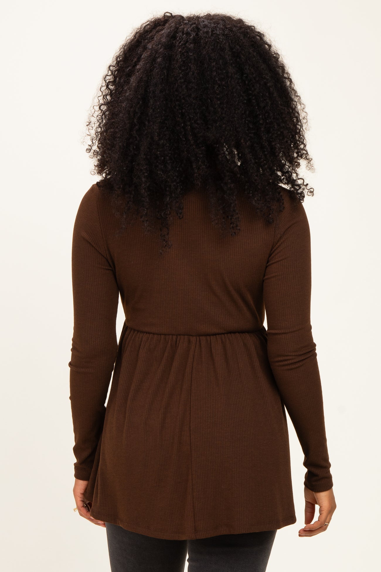 woman wearing a brown long sleeve ribbed top with a gathered waist, viewed from the back
