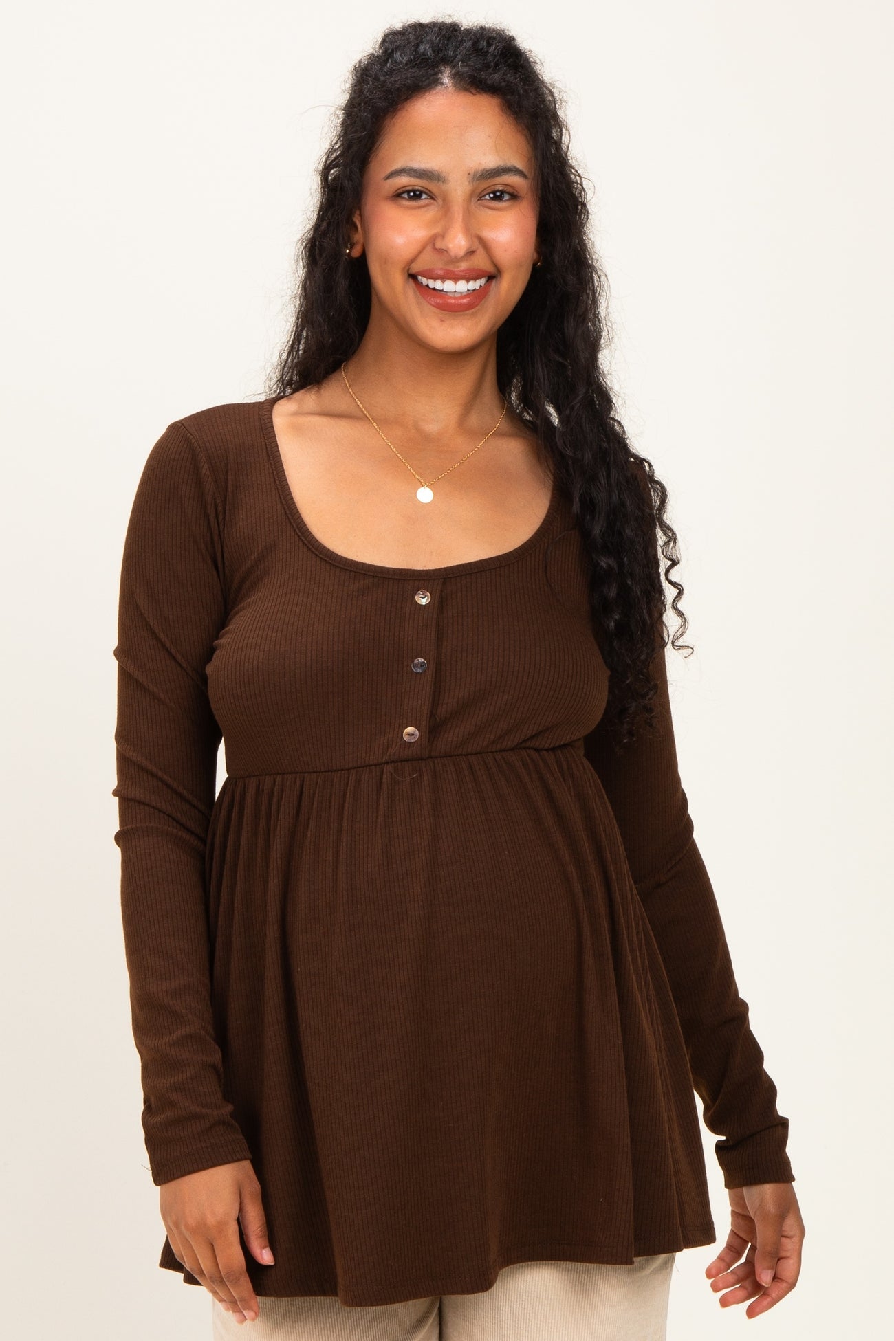 woman wearing a brown ribbed maternity top with button details and a visible baby bump