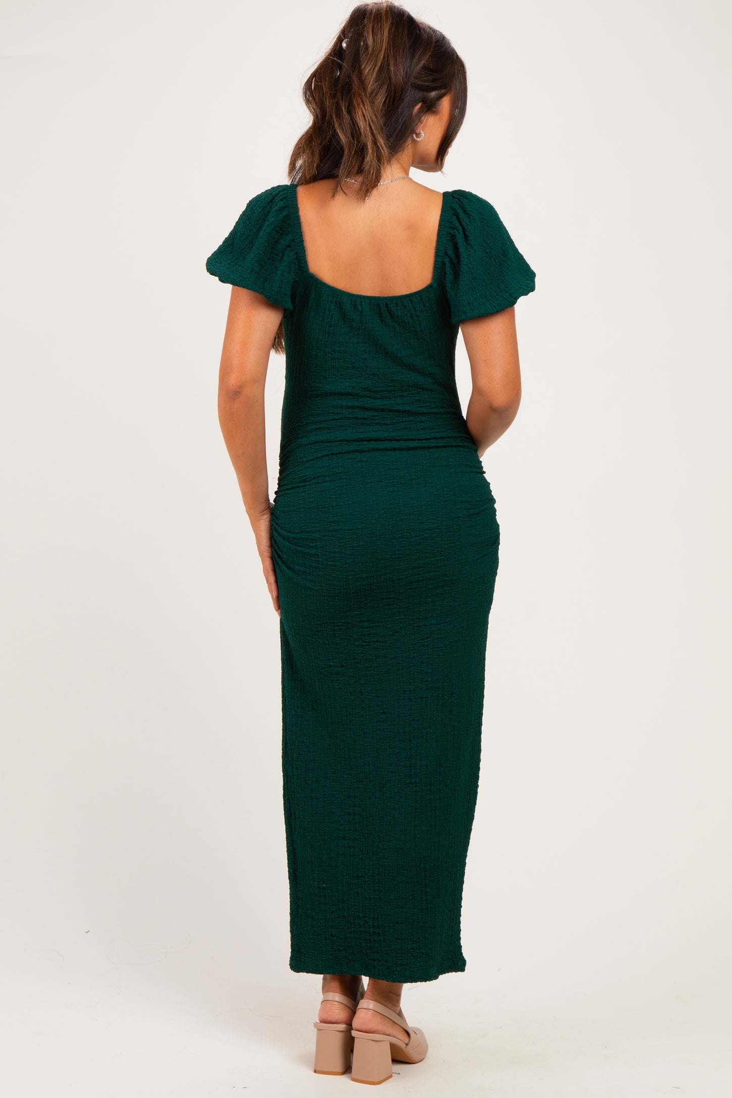 woman wearing a dark green short sleeve maternity dress with a ruched design and a square back detail