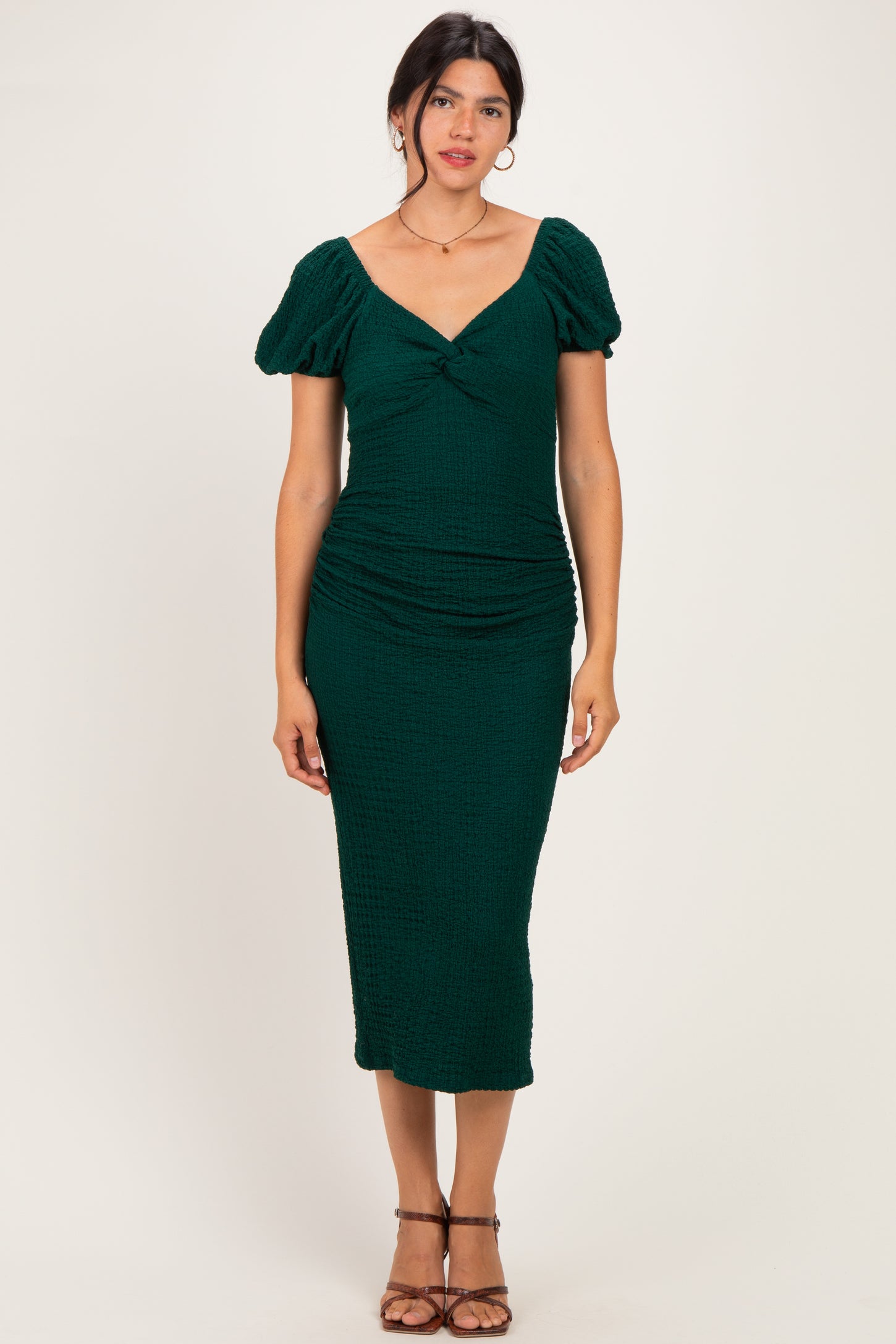 woman wearing a dark green midi dress with puff sleeves and a ruched design
