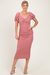 woman wearing a dusty pink fitted midi dress with puff sleeves and a ruched design