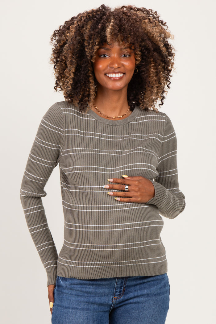 woman wearing a green striped maternity sweater and holding her baby bump
