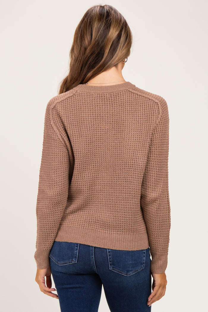 woman wearing a brown textured maternity sweater, showing the back view, paired with dark jeans