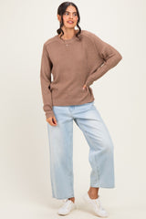 woman wearing a brown waffle-knit oversized sweater and light wash wide-leg jeans, posing with one hand on her hip