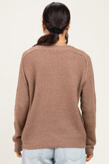 woman wearing a brown textured long sleeve sweater, seen from the back, paired with light blue jeans