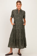 woman wearing a green floral print short sleeve maternity dress with pockets and a tiered skirt