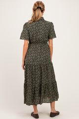 woman wearing a green floral maternity dress with short sleeves and a tiered skirt, showing a baby bump from the back