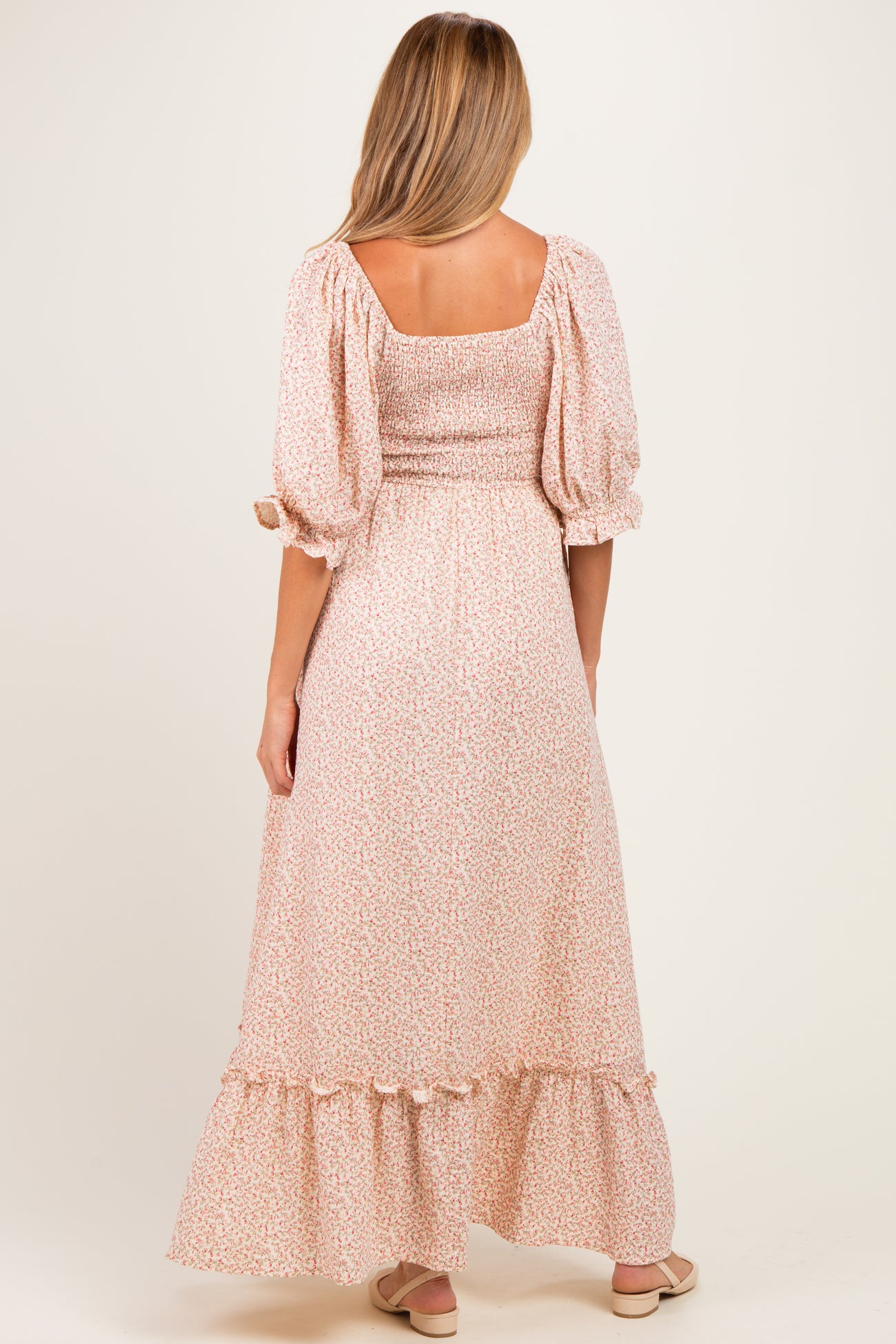 woman wearing a floral print maternity maxi dress with puff sleeves and a ruffled hem