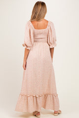 woman wearing a floral print maternity maxi dress with puff sleeves and a ruffled hem